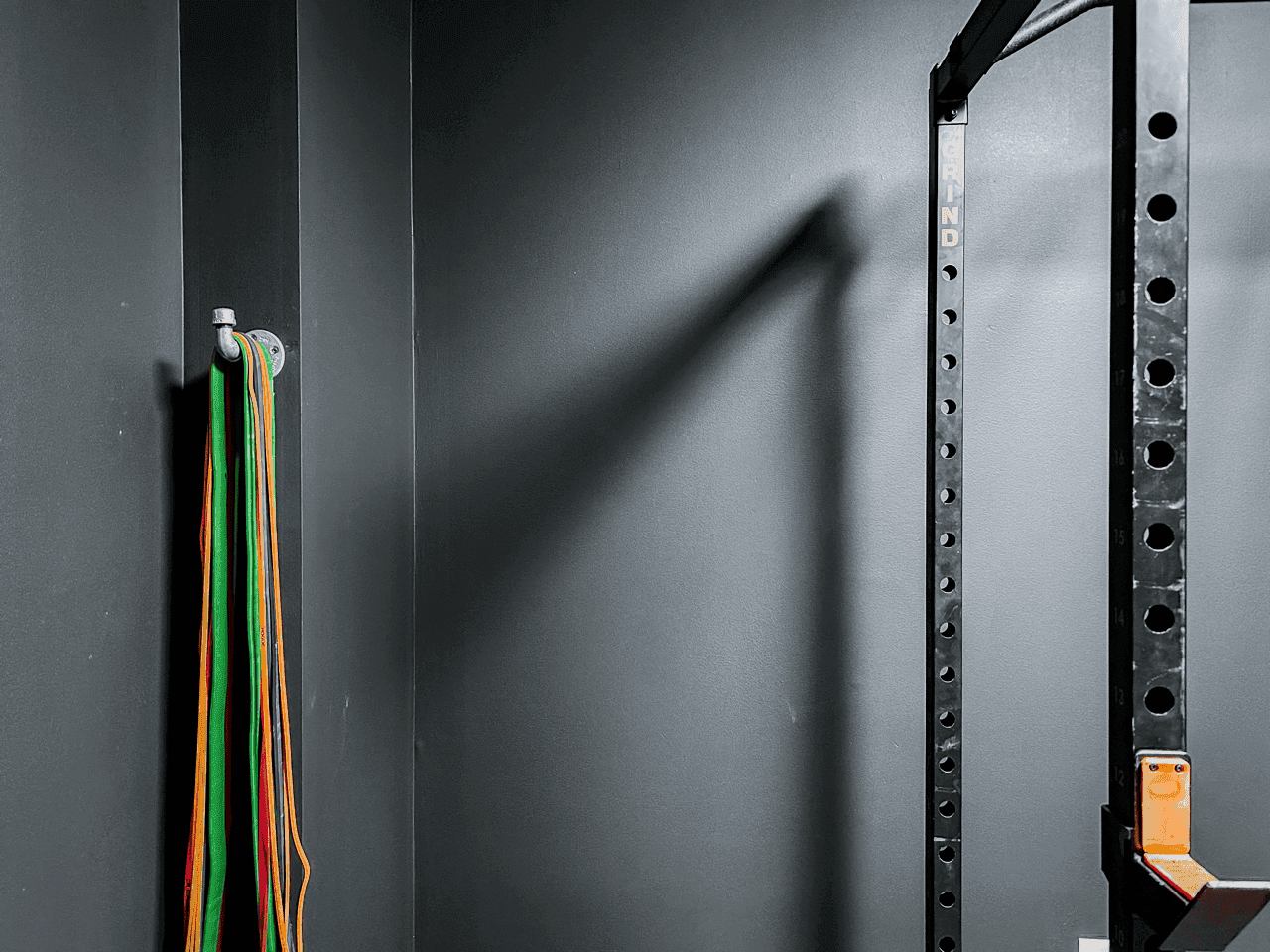 Resistance bands hanging beside the squat rack at Hustle House Health & Wellness in Woodstock, GA