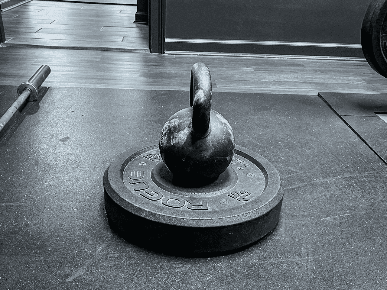 A kettlebell resting on a Rogue weight plate at Hustle House Health & Wellness in Woodstock, GA