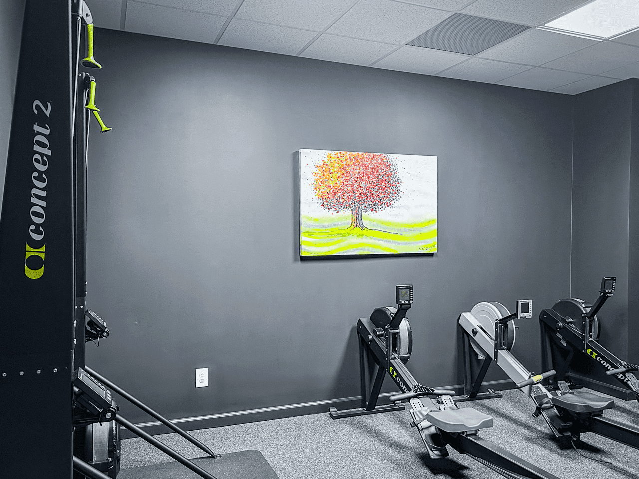 Rowing machines beneath the tree mural at Hustle House Health & Wellness in Woodstock, GA