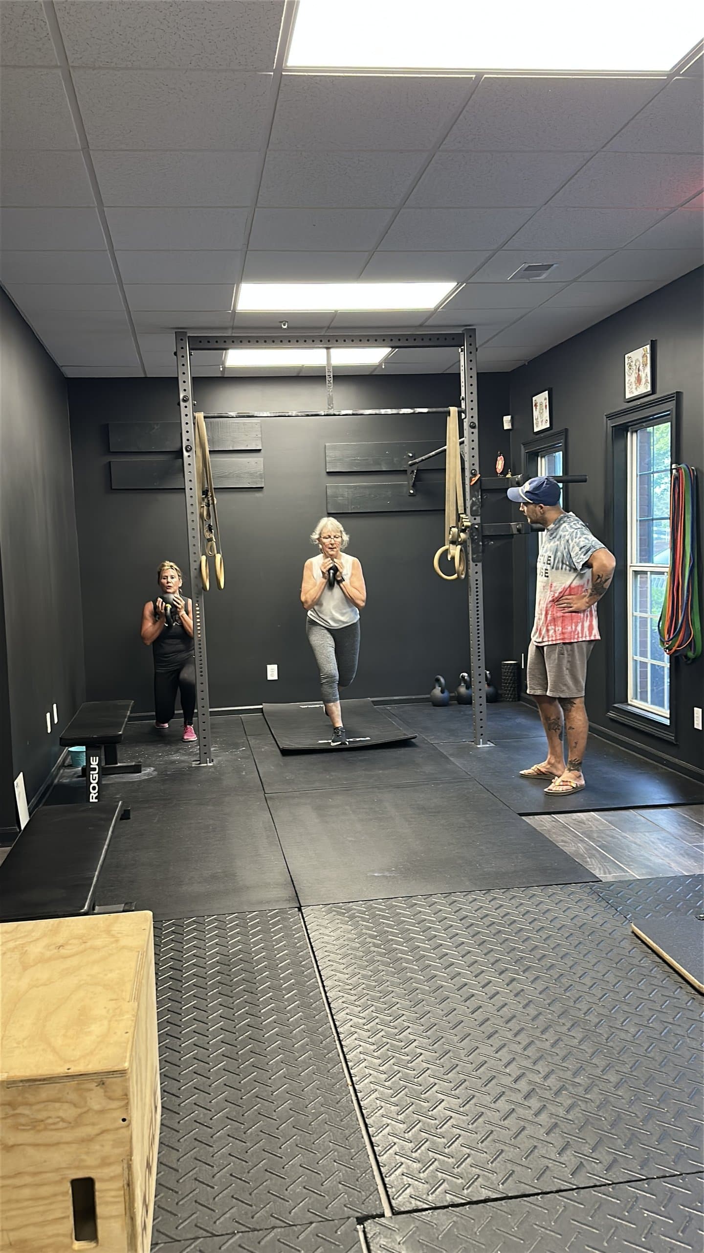 A small group class working on balance beside the squat rack at Hustle House Health & Wellness in Woodstock, GA