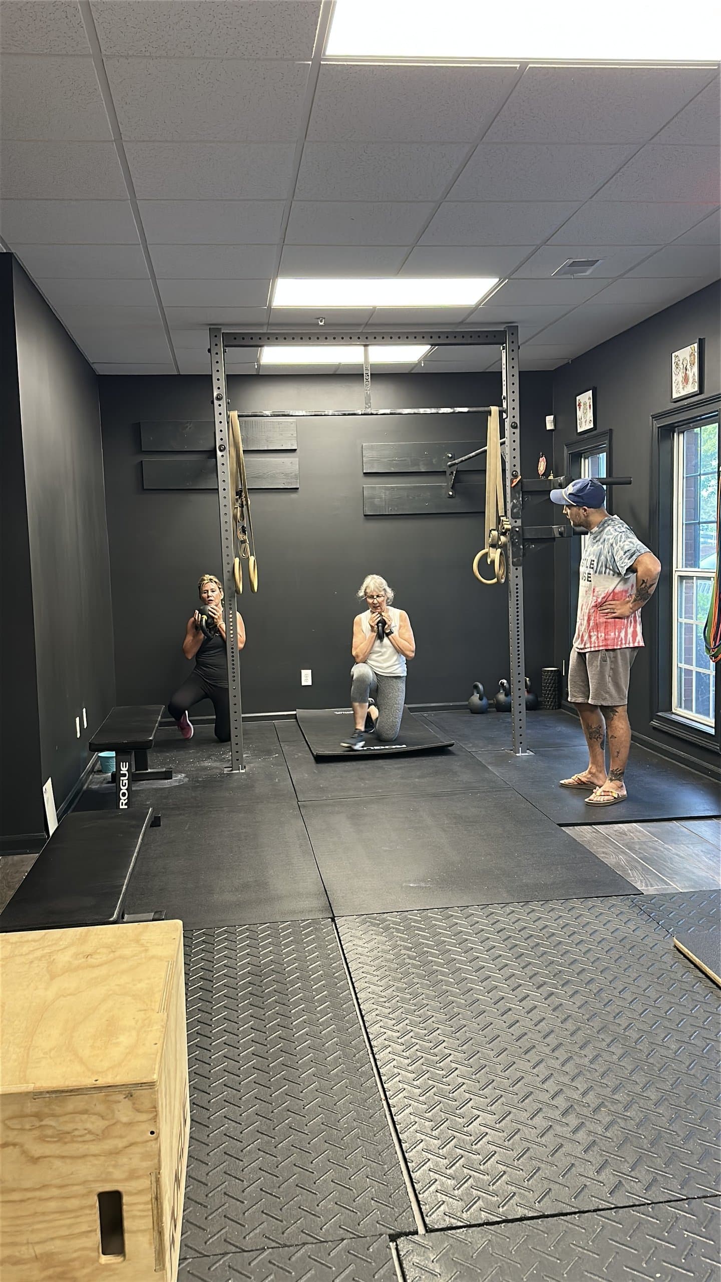 A coach assessing members' movement on the mats at Hustle House Health & Wellness in Woodstock, GA
