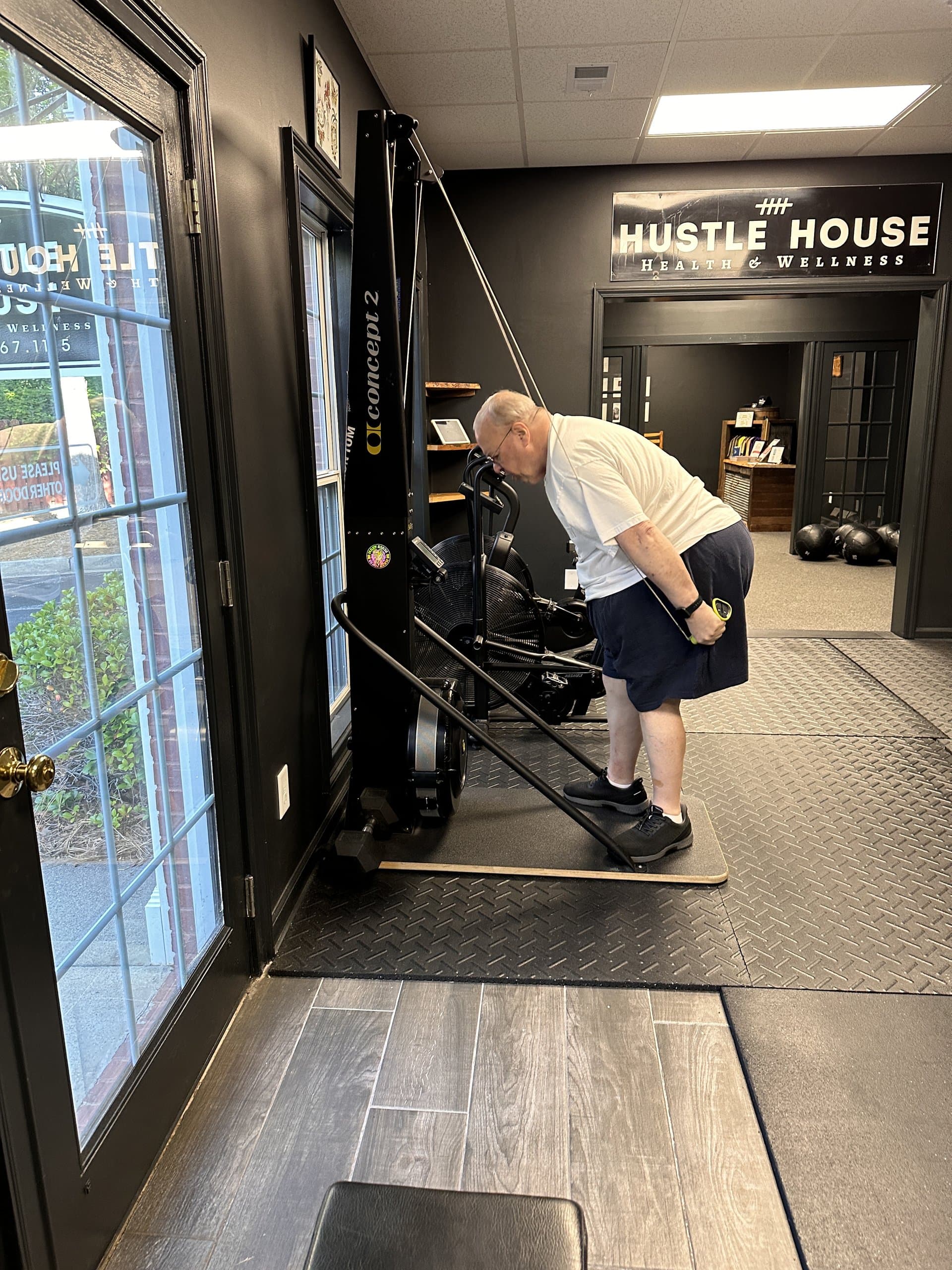 A member using the Concept 2 SkiErg near the studio entrance at Hustle House Health & Wellness in Woodstock, GA