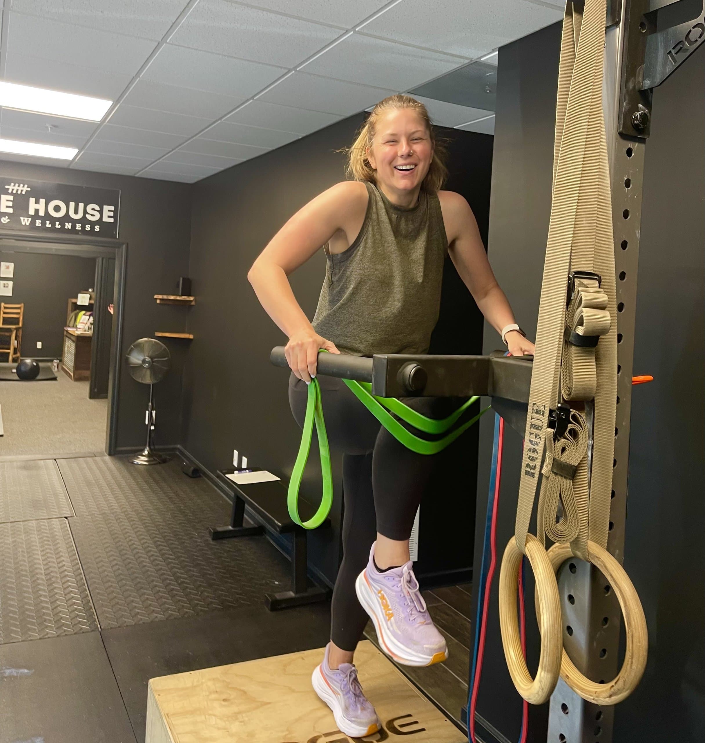 A member performing a band-assisted pull-up at Hustle House Health & Wellness in Woodstock, GA