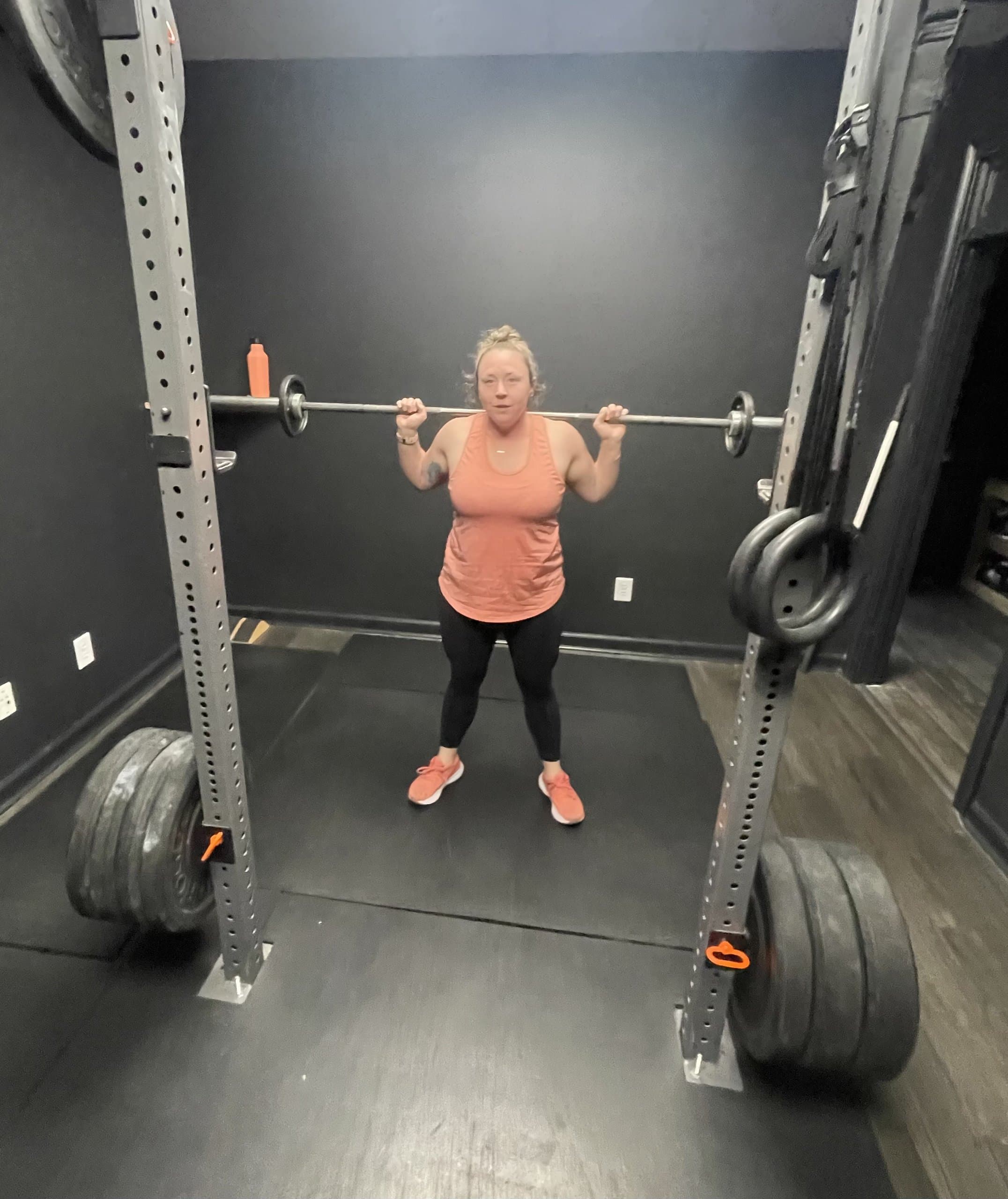A member performing a barbell back squat in the squat rack at Hustle House Health & Wellness in Woodstock, GA