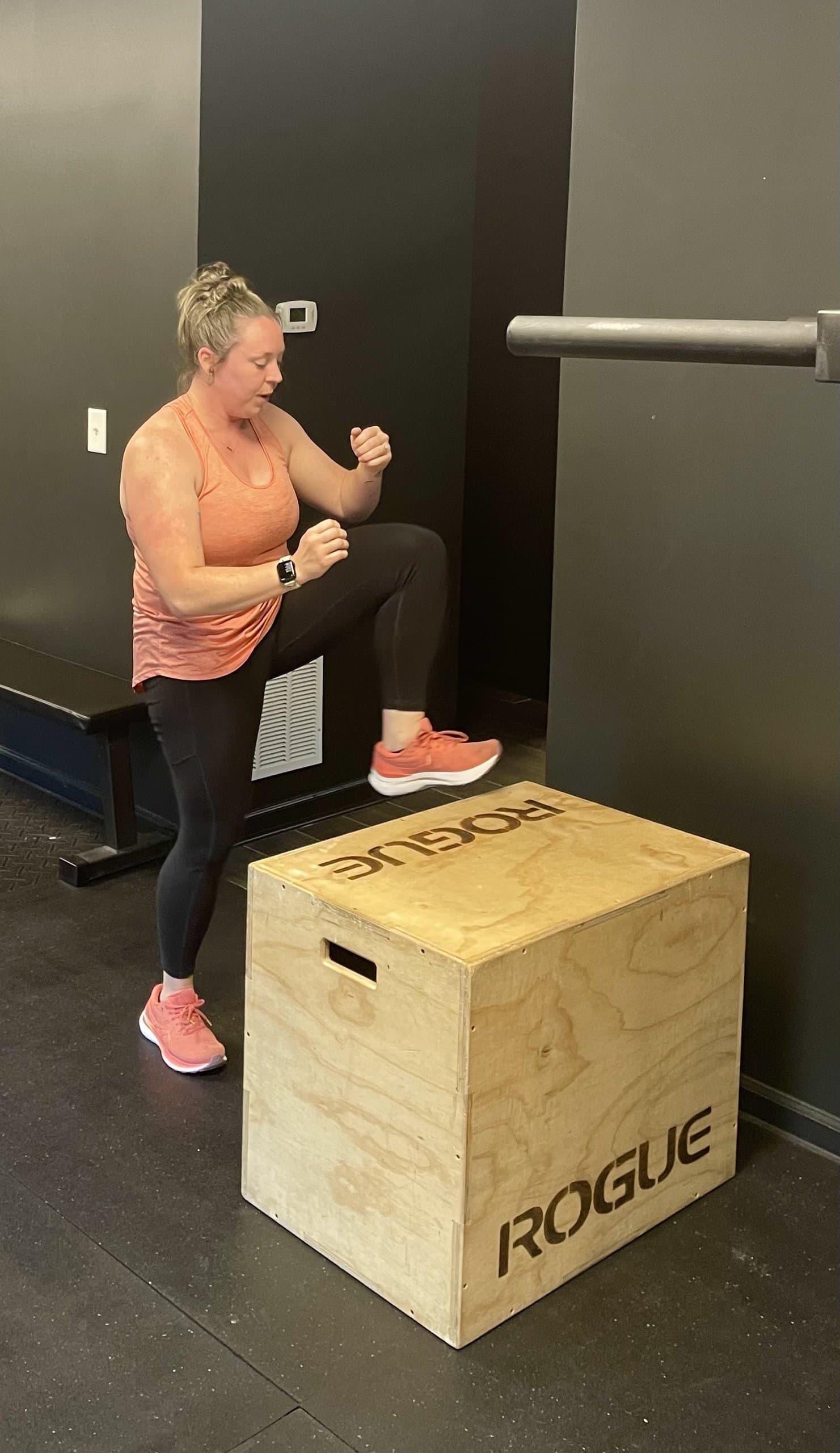 A member performing a step-up onto a wooden plyo box at Hustle House Health & Wellness in Woodstock, GA