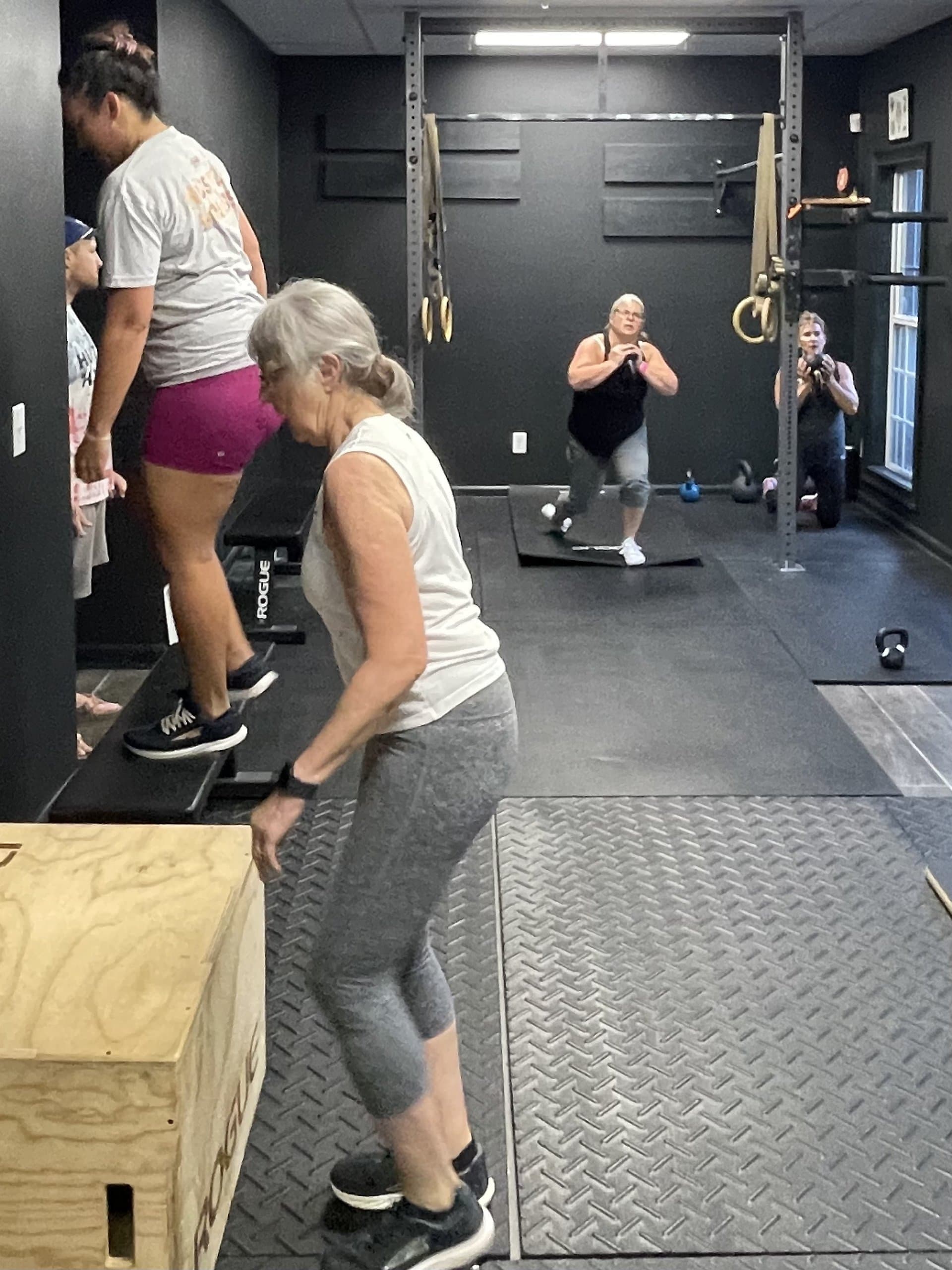 A small group class doing box step-ups and kettlebell lunges at Hustle House Health & Wellness in Woodstock, GA