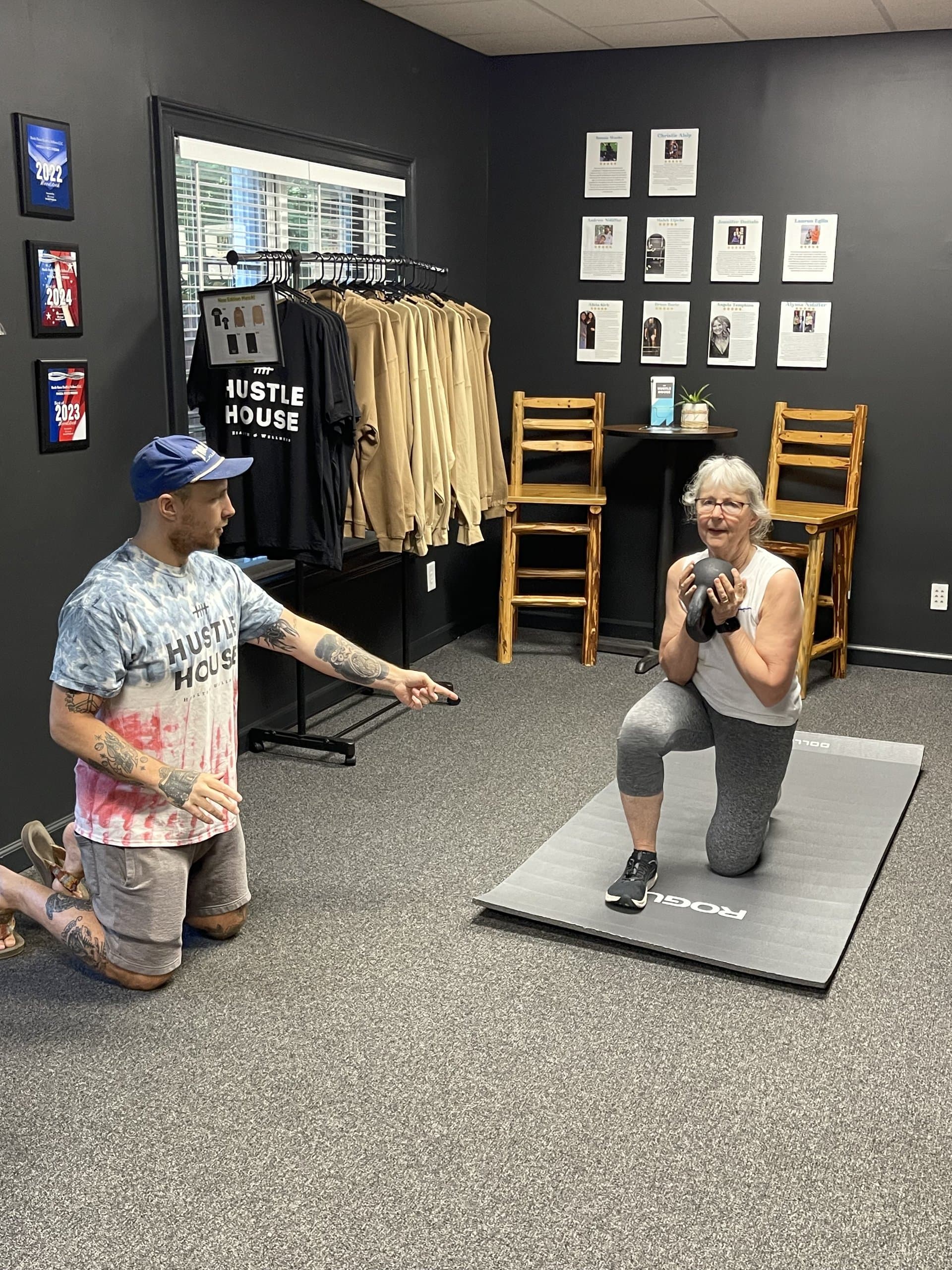 A coach guiding a member through a lunge with a weighted ball at Hustle House Health & Wellness in Woodstock, GA