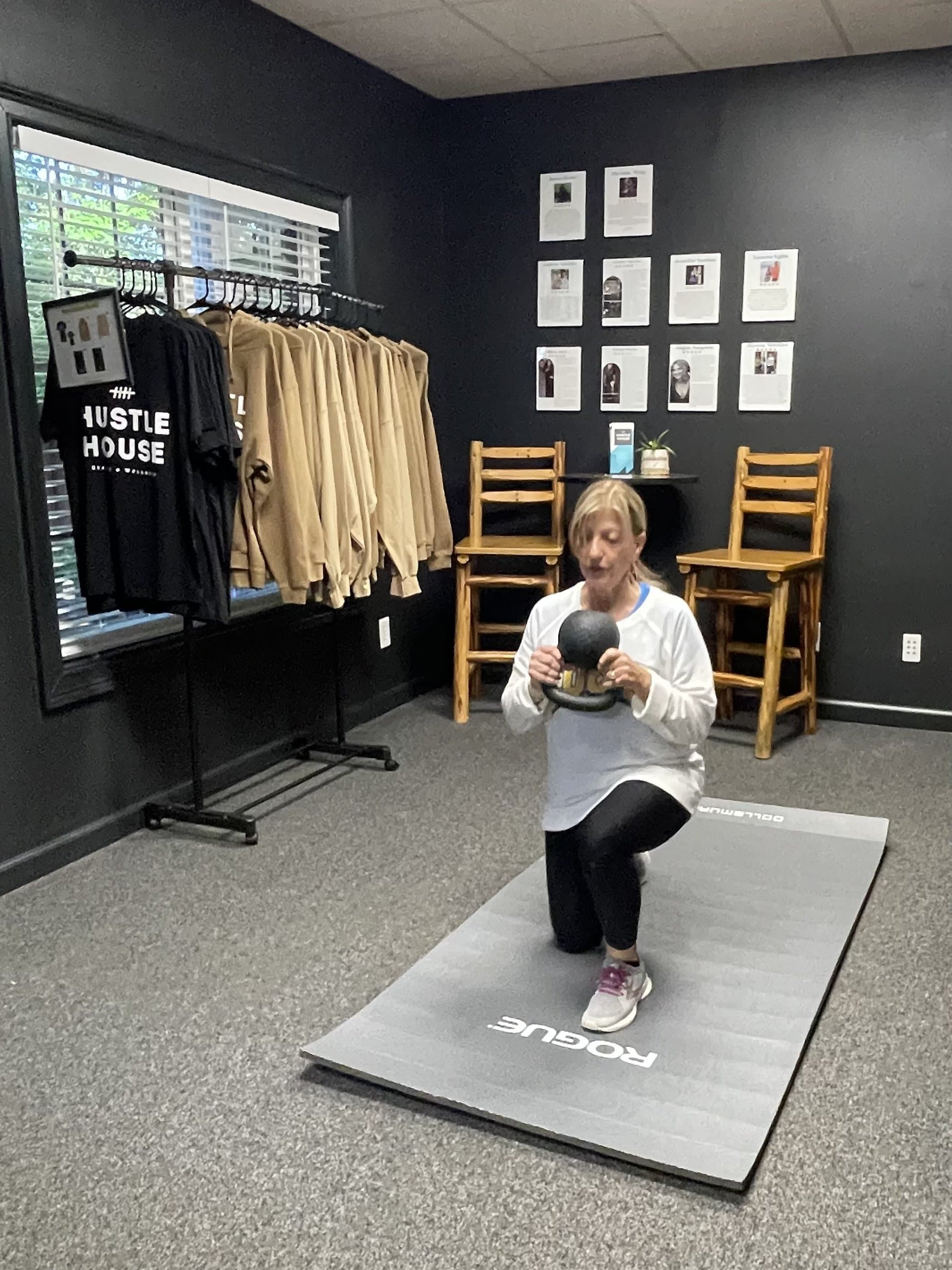 An older member performing a supported lunge with a weighted ball at Hustle House Health & Wellness in Woodstock, GA