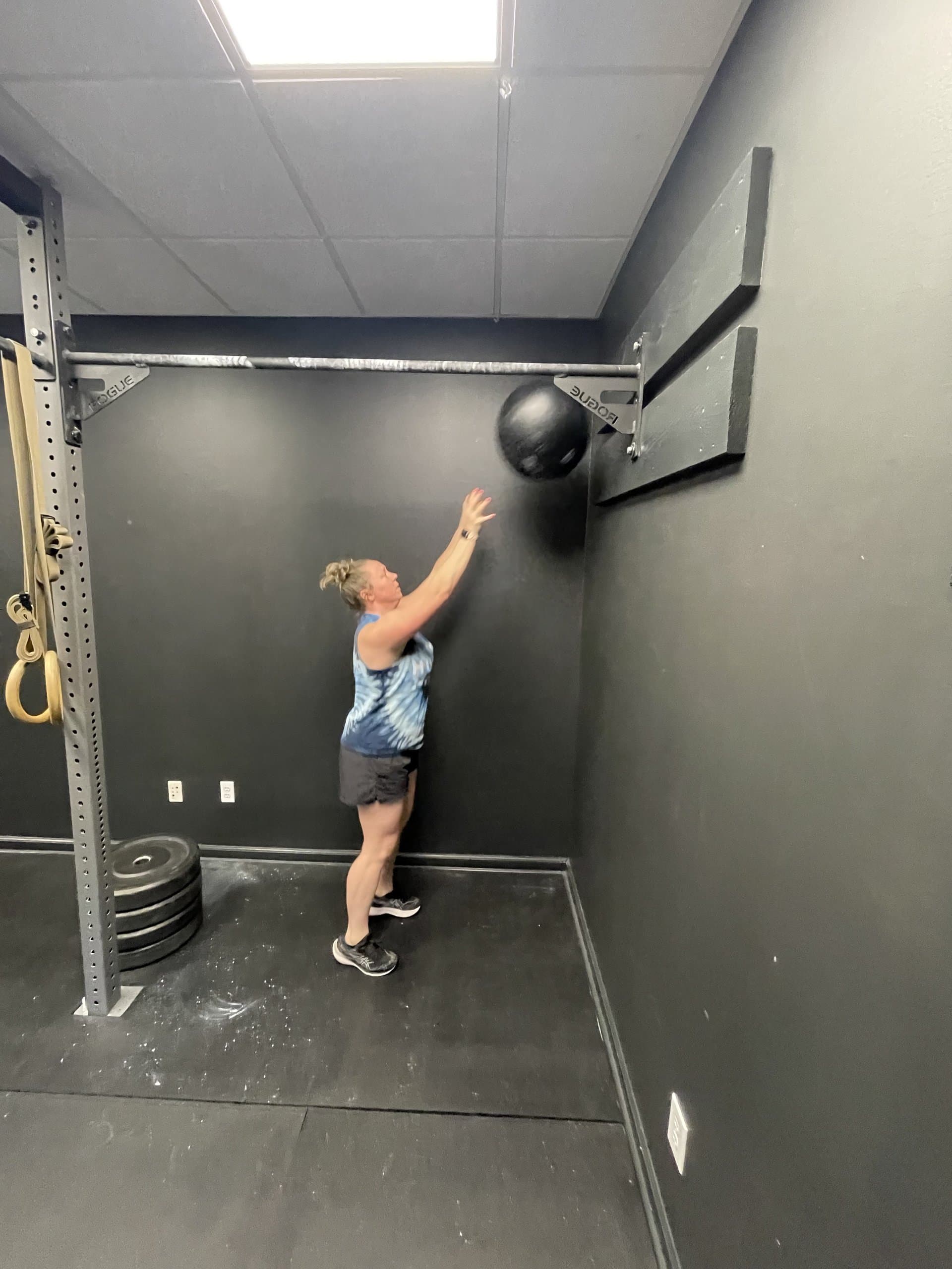 A member throwing a slam ball at the wall target at Hustle House Health & Wellness in Woodstock, GA