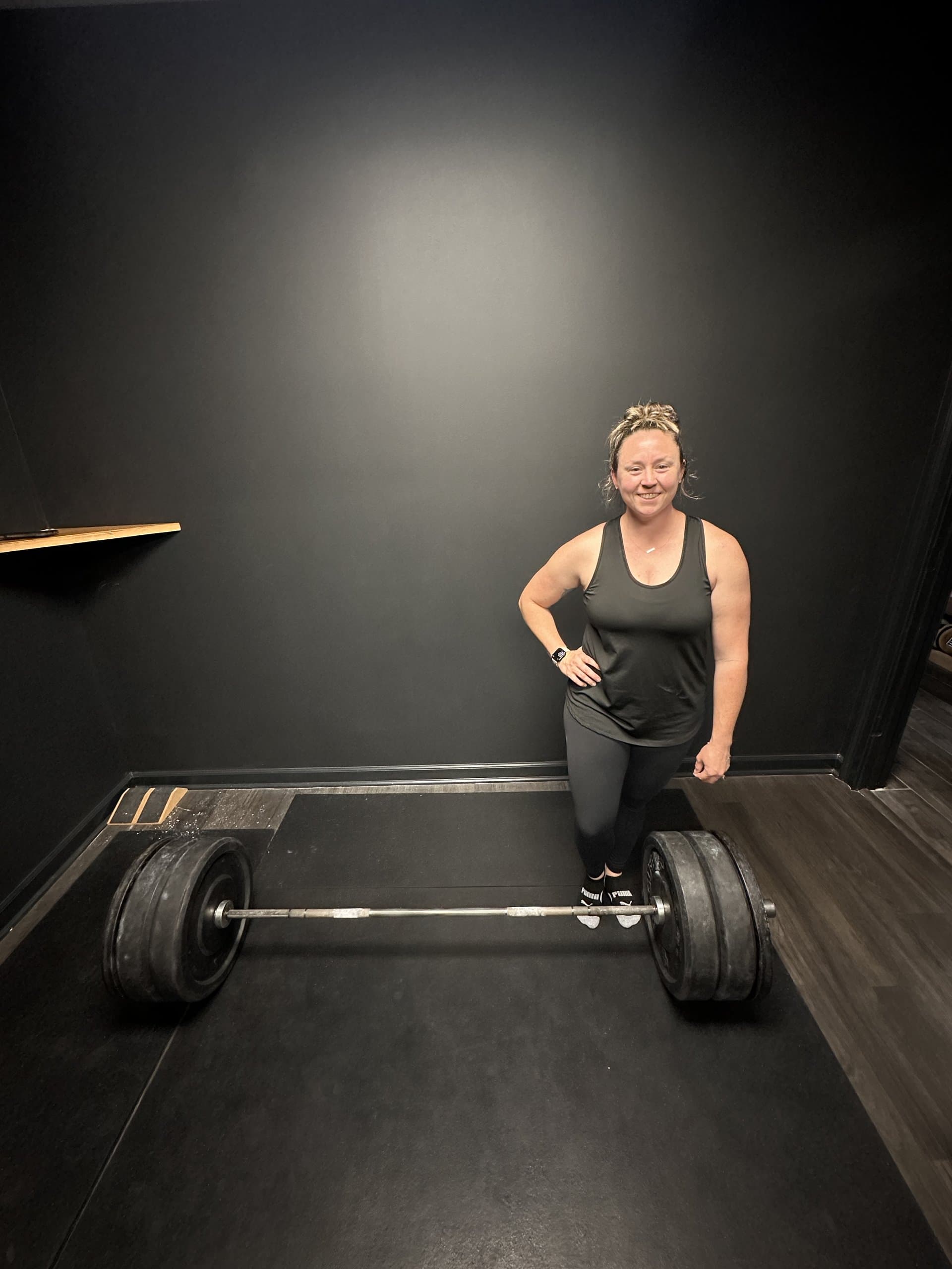 A member beside a heavily loaded barbell at Hustle House Health & Wellness in Woodstock, GA