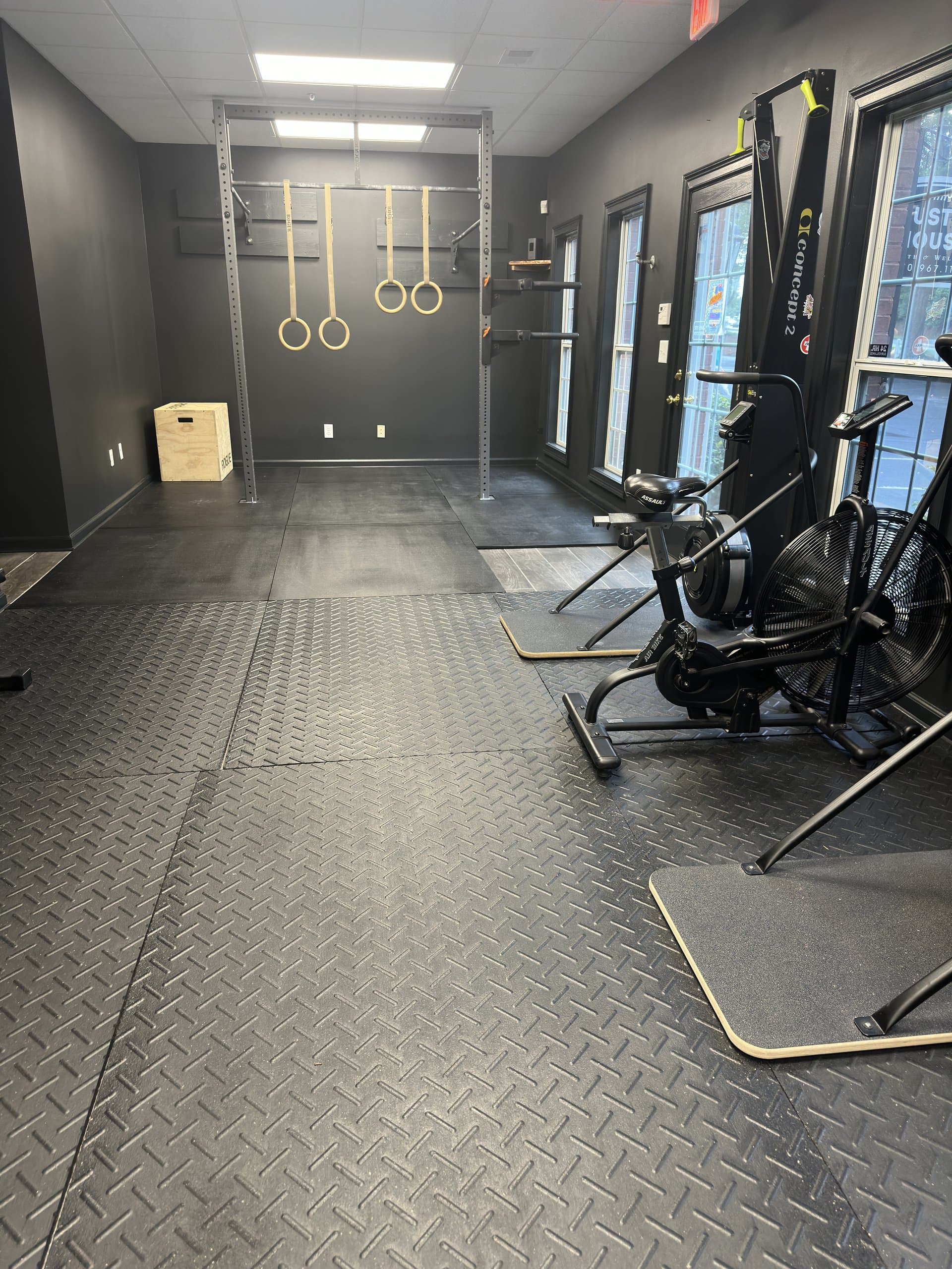 Gymnastic rings and exercise bikes in the training room at Hustle House Health & Wellness in Woodstock, GA