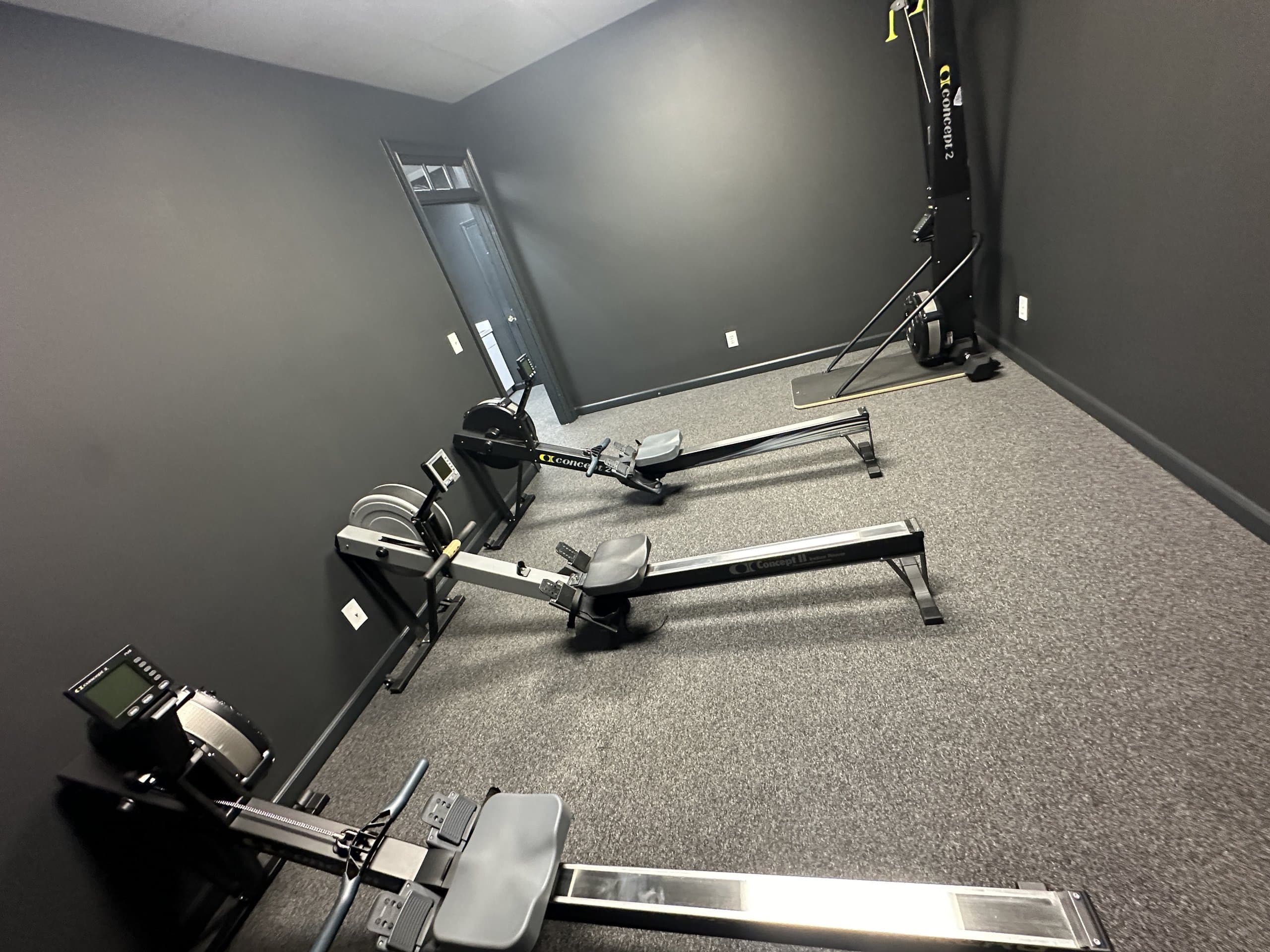 Rowing machines arranged near the doorway at Hustle House Health & Wellness in Woodstock, GA