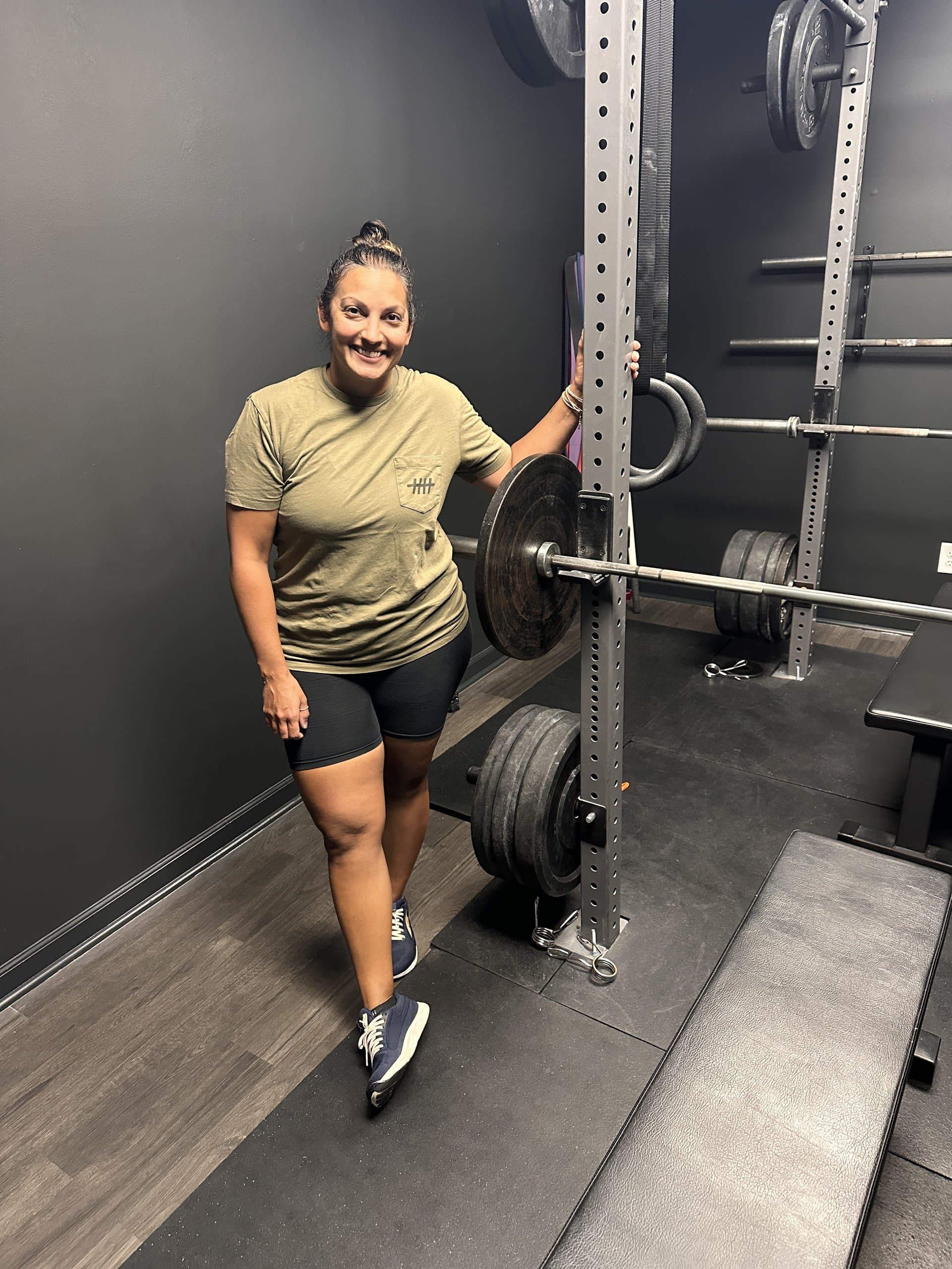 A member beside a loaded barbell in the squat rack at Hustle House Health & Wellness in Woodstock, GA