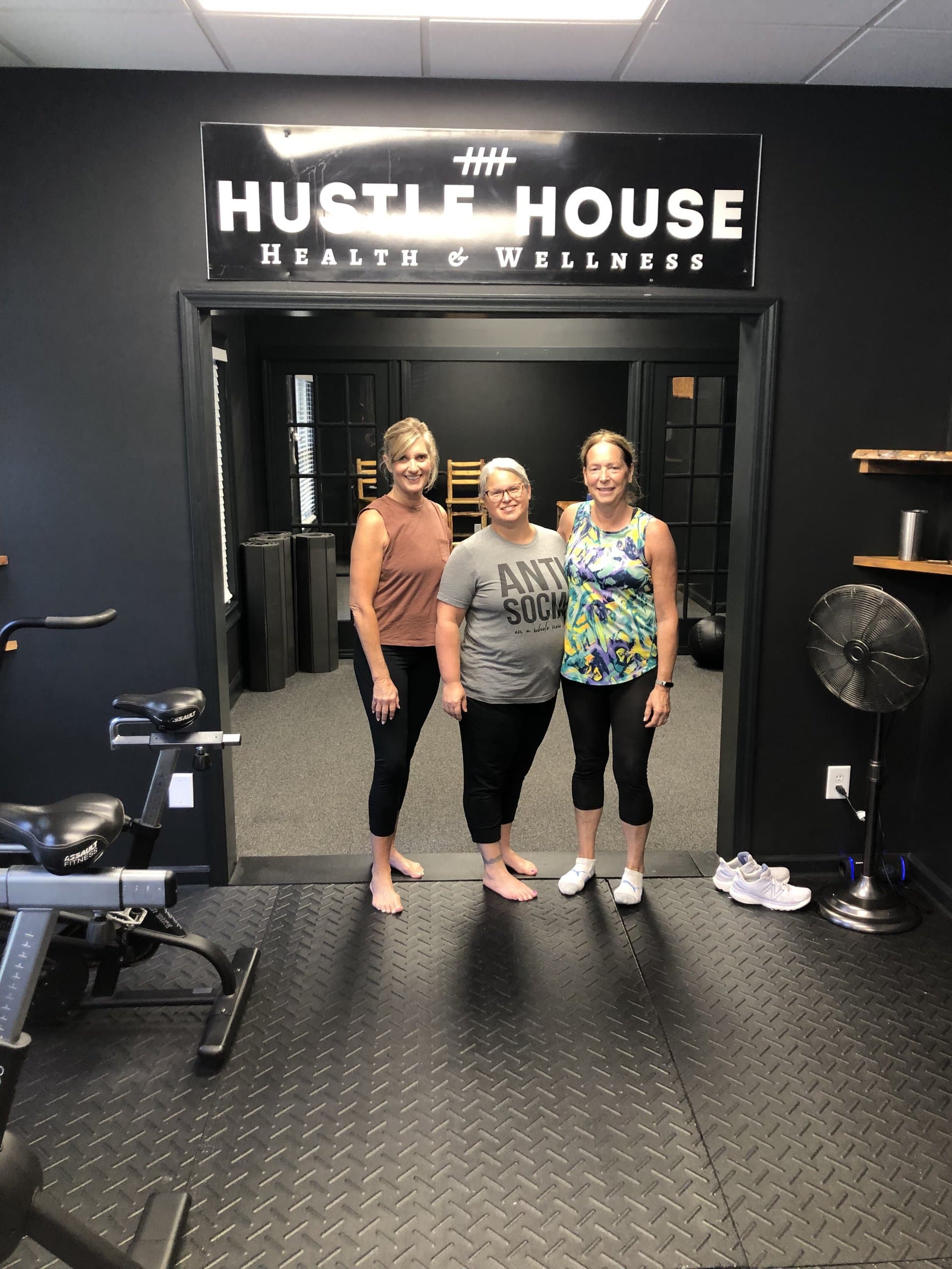 Members beneath the Hustle House Health & Wellness sign in Woodstock, GA
