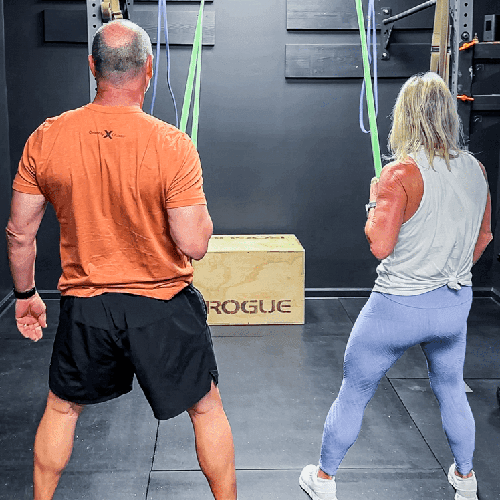 Members performing resistance band work beside a Rogue plyo box at Hustle House Health & Wellness in Woodstock, GA